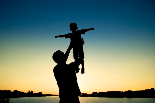 Silhouette di padre e figlio giocano sul tramonto