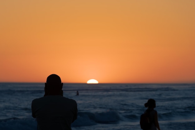 Silhouette di persona che guarda il tramonto nel mare