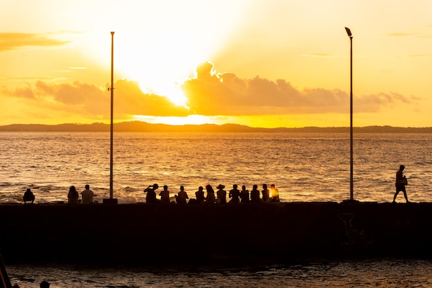 Silhouette di persone al tramonto sul molo di Porto da Barra nella città di Salvador Bahia