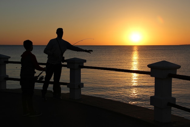 Silhouette di persone che pescano con il colore giallo del tramonto