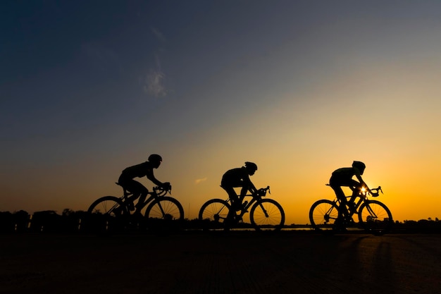 Silhouette di persone in bicicletta per strada contro il cielo durante il tramonto