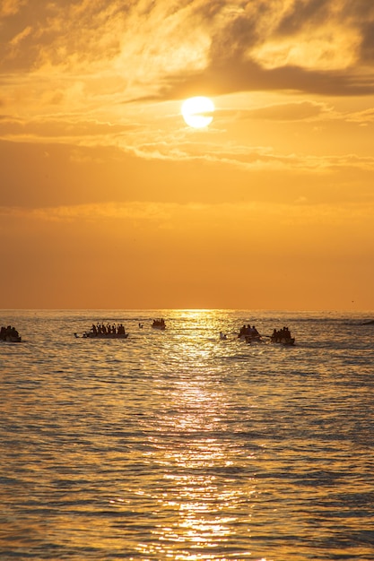 Silhouette di persone in canoa all'alba sulla spiaggia di Copacabana a Rio de Janeiro