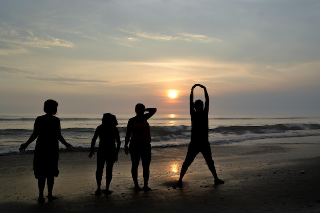 Silhouette di quattro persone che giocano in riva al mare al tramonto Golden hour