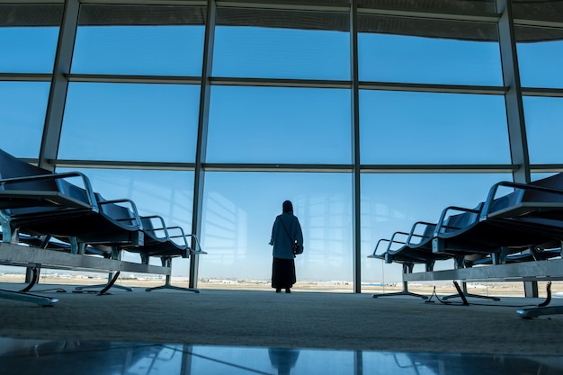 Silhouette di sedili d'attesa dell'aeroporto e finestra con cielo blu