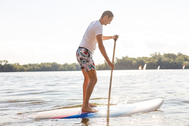 Silhouette di stand up paddle boarder che rema al tramonto