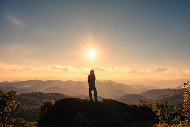 Silhouette di successo giovane escursionista donna in piedi sulla cima del picco di montagna al tramonto al parco nazionale