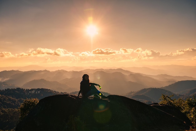 Silhouette di successo giovane escursionista donna rilassante e godersi la vista del tramonto sulla cima del picco di montagna al parco nazionale