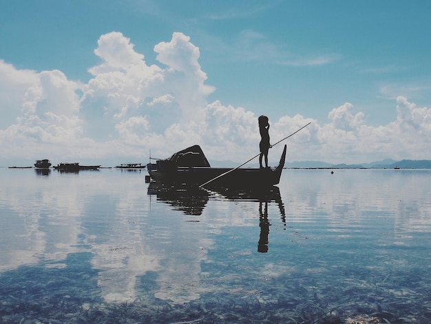 Silhouette di un bambino su una barca da pesca