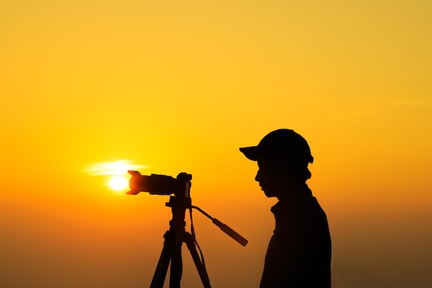 Silhouette di un fotografo con treppiede Giovane uomo indiano che scatta foto con la sua macchina fotografica