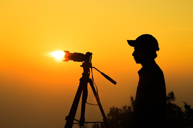Silhouette di un fotografo con treppiede Giovane uomo indiano che scatta foto con la sua macchina fotografica
