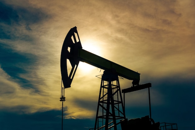 Silhouette di un pumpjack con pompa a pistone su un pozzo petrolifero sullo sfondo del cielo