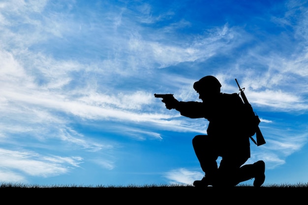 Silhouette di un soldato con una pistola in esplorazione sullo sfondo del cielo