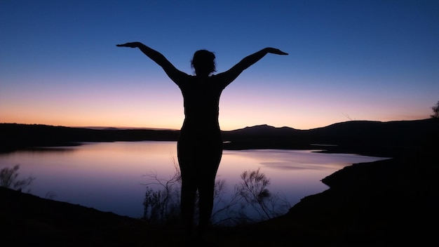 Silhouette di un uomo in piedi vicino al lago contro il cielo durante il tramonto