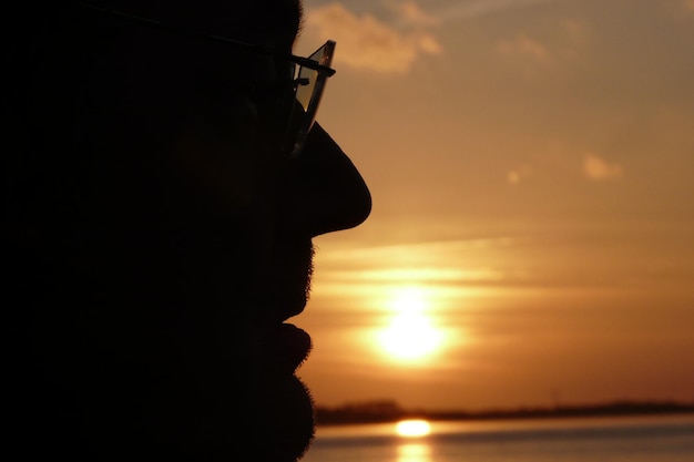 Silhouette di un uomo sul mare durante il tramonto