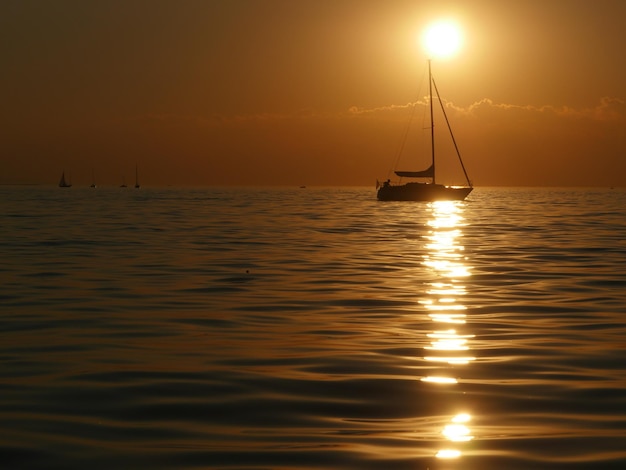 Silhouette di una barca a vela che naviga sul mare contro il cielo durante il tramonto