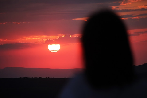 Silhouette di una donna che guarda un tramonto rosso Giovane donna alla luce del tramonto che guarda lontano