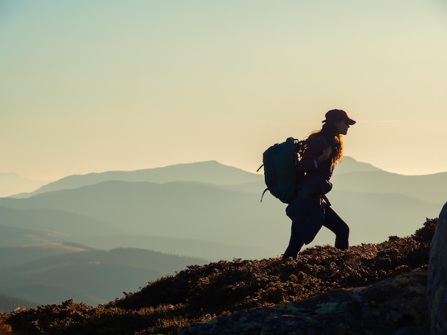 Silhouette di una donna turista escursionista con uno zaino durante un trekking in montagna