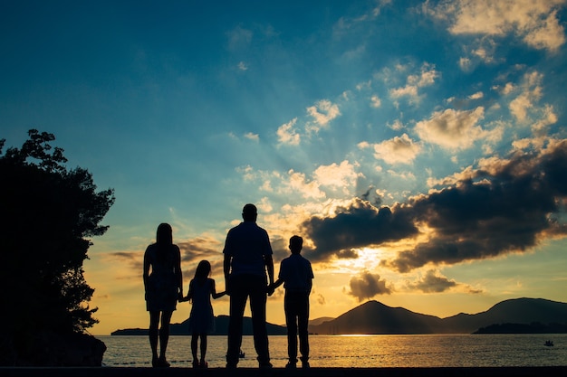 Silhouette di una famiglia con bambini sullo sfondo del sole al tramonto e del mare in Montenegro.