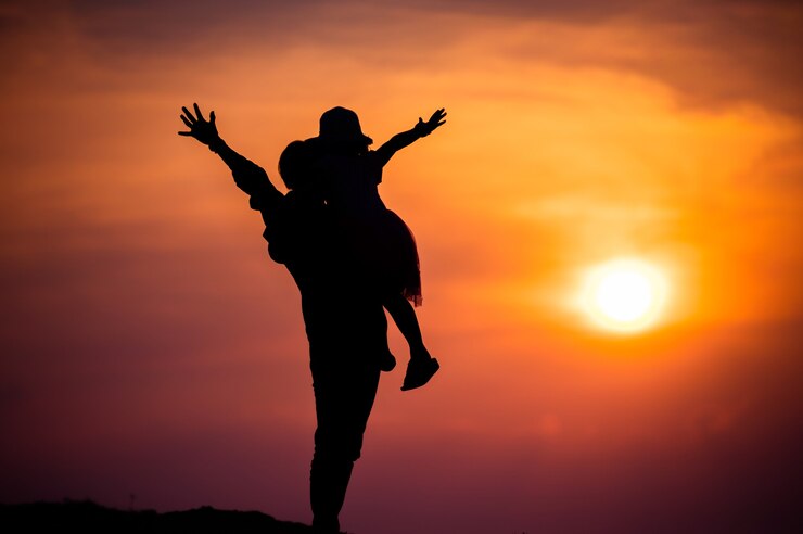 Silhouette di una famiglia con una madre felice che gioca con una ragazza nel cielo al tramonto