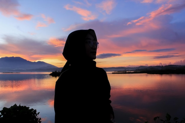 Silhouette di una giovane donna in posa su uno sfondo bellissimo tramonto