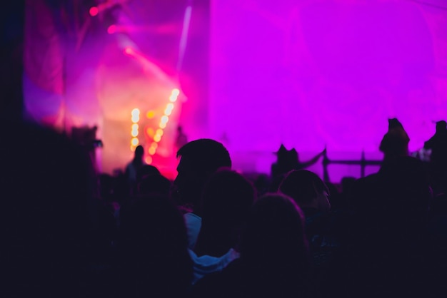 Silhouette di una grande folla al concerto contro un concerto rock notturno sul palco ben illuminato con