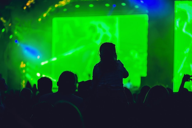 Silhouette di una grande folla al concerto contro un concerto rock notturno sul palco ben illuminato con