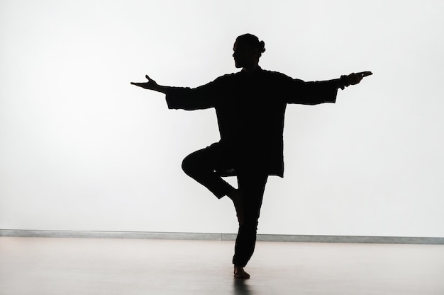 Silhouette di una persona che pratica esercizi di energia qigong su uno sfondo chiaro