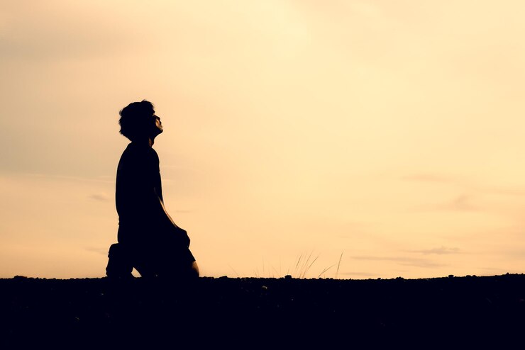 Silhouette di uomini seduti e che pregano per le benedizioni concetto di speranza