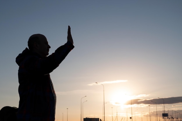 Silhouette di uomo di mezza età che agita la mano in piedi da solo al mattino