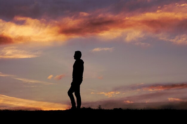 silhouette di uomo nella campagna e sullo sfondo del tramonto