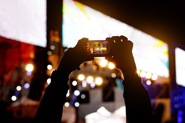 Silhouette di utilizzare un telefono cellulare a un concerto.