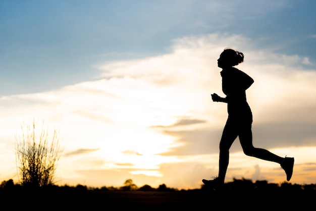 Silhouette donna che corre da sola al bel tramonto nel parco.