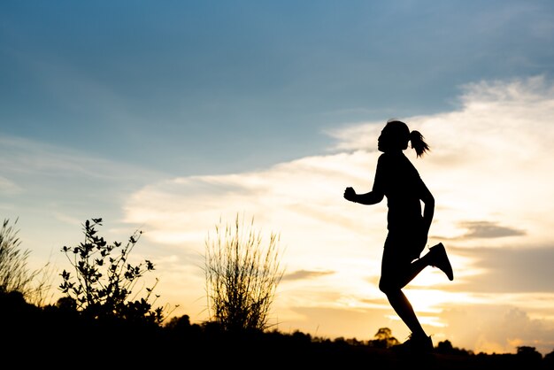 Silhouette donna che corre da sola al bel tramonto nel parco.