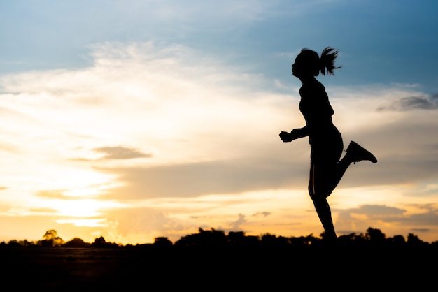 Silhouette donna che corre da sola al bel tramonto nel parco.