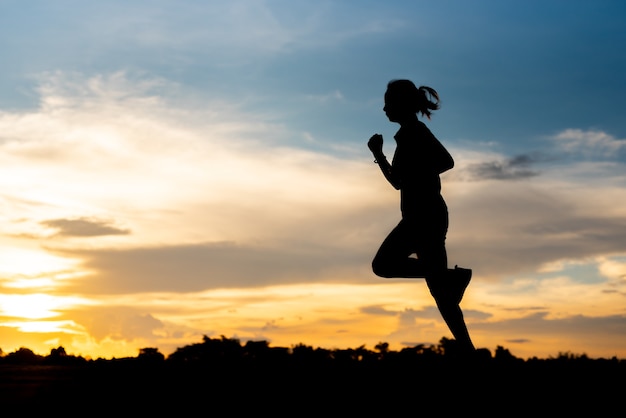 Silhouette donna che corre da sola al bel tramonto nel parco.