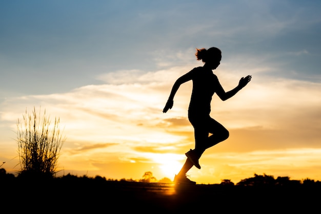 Silhouette donna che corre da sola al bel tramonto nel parco.