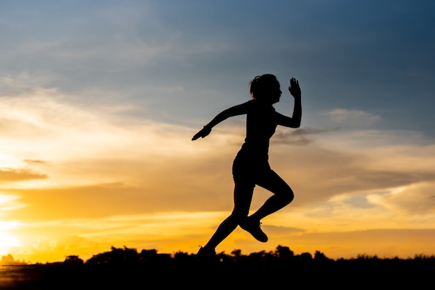 Silhouette donna che corre da sola al bel tramonto nel parco.