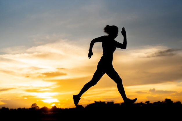 Silhouette donna che corre da sola al bel tramonto nel parco.