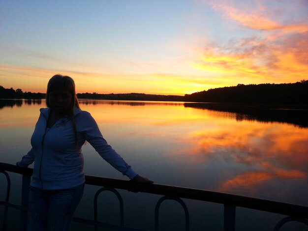 Silhouette donna in piedi dalla ringhiera contro il cielo durante il tramonto