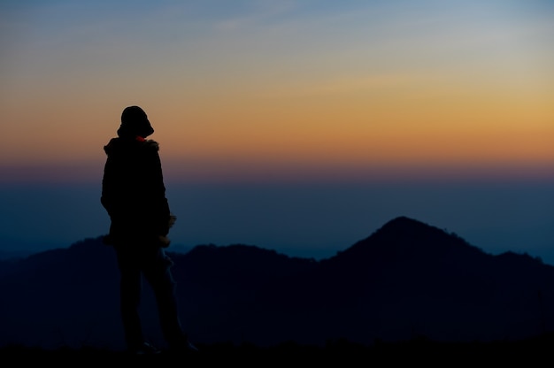 Silhouette donna triste sulla montagna al tramonto e filtro vintage