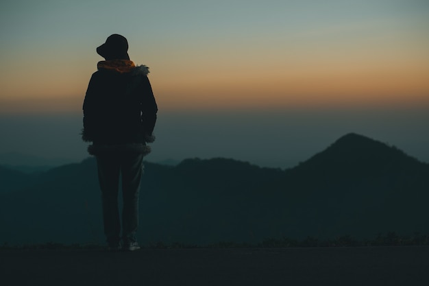 Silhouette donna triste sulla montagna al tramonto e filtro vintage