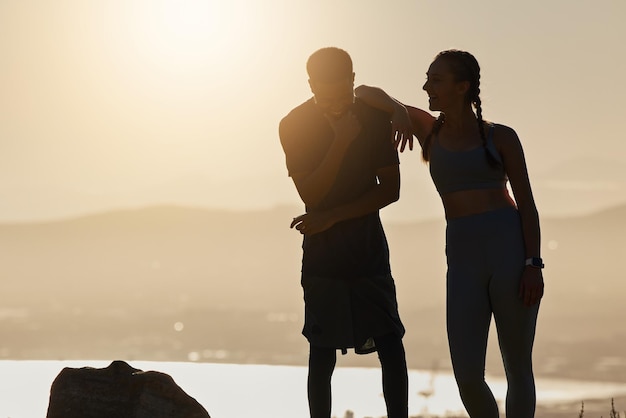 Silhouette fitness e coppia che parlano nella natura in pausa dopo l'allenamento all'aperto Tramonto felice uomo e donna che discutono obiettivi di allenamento o bersaglio insieme dopo aver corso o esercitato per il benessere