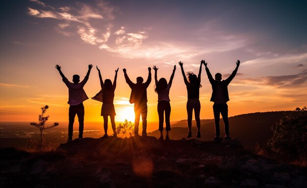 Silhouette fotografica di una squadra d'affari felice che alza le mani sullo sfondo del cielo al tramonto