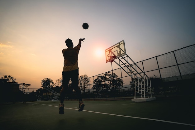 Silhouette giocatore di basket al tramonto giocatore di basket spara un colpo Concetto di basket sportivo