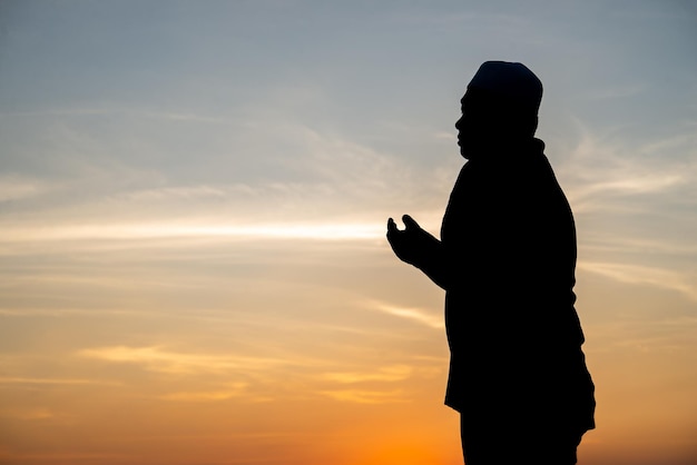 Silhouette Giovane uomo musulmano asiatico che prega sul concetto di festival del tramontoRamadan