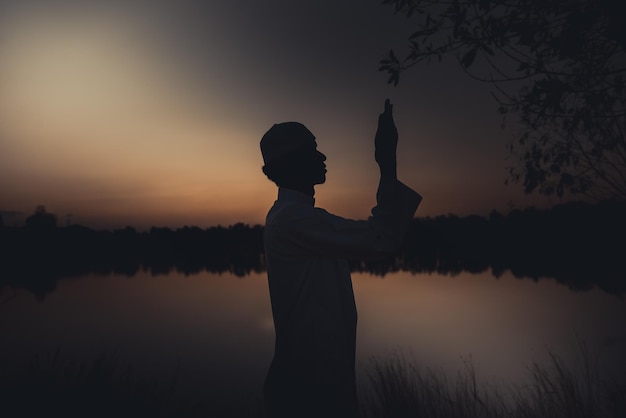 Silhouette Giovane uomo musulmano asiatico che prega sul concetto di festival del tramontoRamadan