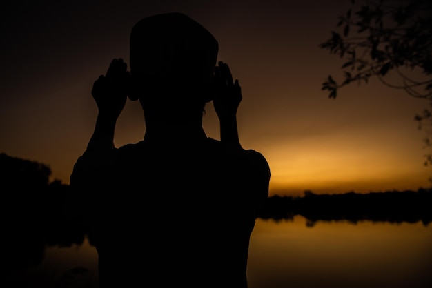 Silhouette Giovane uomo musulmano asiatico che prega sul concetto di festival del tramontoRamadan