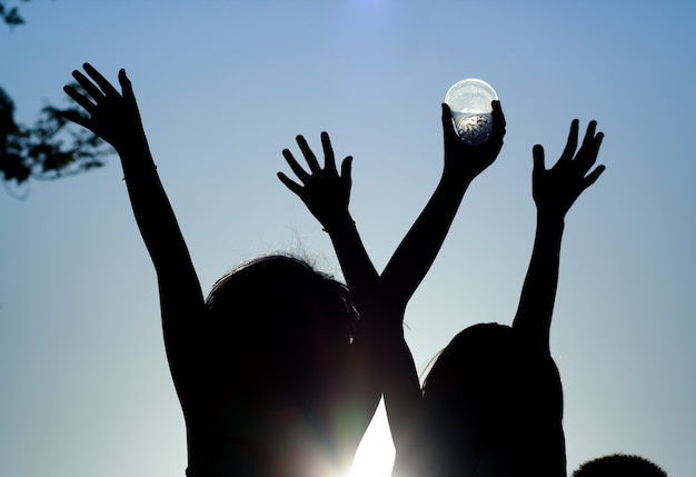 Silhouette, gruppo di bambini felici che giocano sulla priorità bassa di tramonto.