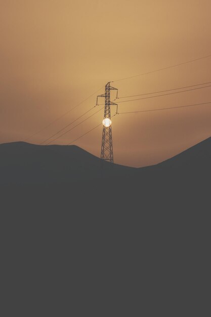 Silhouette pilone elettrico contro il cielo durante il tramonto