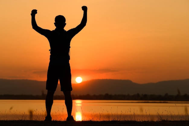 Silhouette tramonto di felice uomo gioioso che salta e si diverte, il concetto di lotta per il successo aziendale della vittoria Libertà